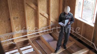 建筑师或建筑商检查半建木框架房屋的计划。 建筑工地上的建筑工人